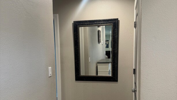 A hallway with a wooden floor, a mirror with a black frame, and a door on the right. - Wonderful 4-bedroom Home Base in Phoenix- Freeway Access- Close to everything! (Phoenix)