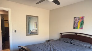 A bedroom with a bed, a ceiling fan, a mirror, and a painting on the wall. - Wonderful 4-bedroom Home Base in Phoenix- Freeway Access- Close to everything! (Phoenix)