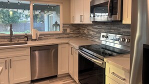 A modern kitchen with stainless steel appliances, a dishwasher, and a window with a view of the outdoors. - Wonderful 4-bedroom Home Base in Phoenix- Freeway Access- Close to everything! (Phoenix)