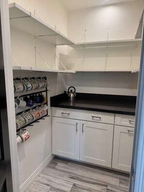A kitchen with white cabinets, a black countertop, and a kettle. - Wonderful 4-bedroom Home Base in Phoenix- Freeway Access- Close to everything! (Phoenix)