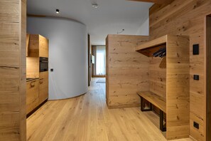 Ein modernes Interieur mit Holzvertäfelung, einer Küchenzeile mit Geräten und einer Bank mit aufgehängten Gegenständen.