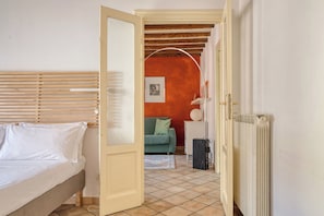 A bedroom with a bed, a door leading to another room, and a radiator. - Bright 1BR with Balcony in Navigli (Milano)