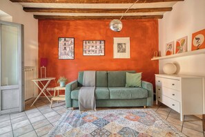 A cozy living room with a green sofa, a patterned rug, and artwork on the walls. - Bright 1BR with Balcony in Navigli (Milano)