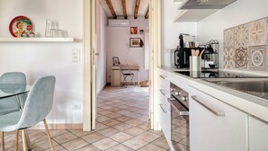 A kitchen with a dining area, a chair, a table, and a kitchen counter. - Bright 1BR with Balcony in Navigli (Milano)