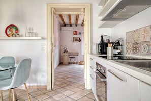 A kitchen with a dining area, a chair, a table, and a kitchen counter. - Bright 1BR with Balcony in Navigli (Milano)