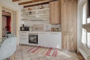 A modern kitchen with white cabinets, a built-in oven, and a wooden ceiling. - Bright 1BR with Balcony in Navigli (Milano)