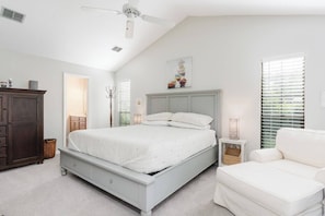 A bedroom with a bed, a dresser, a chair, and a ceiling fan.