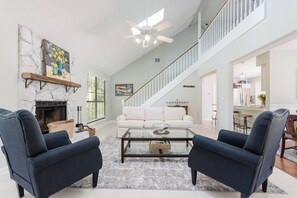 A spacious living room with a fireplace, a staircase, and a dining area.