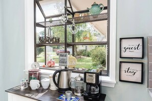 A kitchen counter with a coffee maker, mugs, and a sign that reads 'Today's good mood is brought to you by Coffee.'