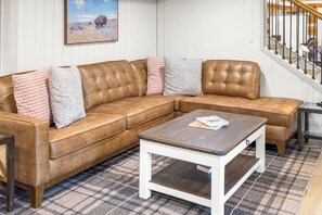 Ein modulares Sofa mit einem karierten Teppich, einem Couchtisch und einer Treppe mit Geländer.