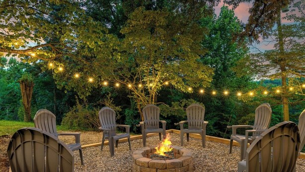 Un'area salotto circolare attorno a un braciere, con luci decorative appese sopra.