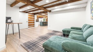 Un soggiorno moderno con soffitto in legno, un divano verde, un tavolino da caffè e, sullo sfondo, un angolo cottura.