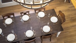 Un tavolo da pranzo imbandito per sei persone, con un lampadario sopra, sedie in legno e pavimento in legno.