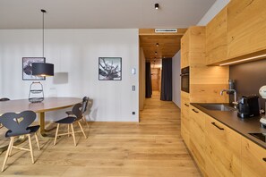 A modern kitchen with wooden cabinets, a built-in oven, and a coffee machine. - 8002 Alpin Retreat Grand 2 (Schröcken)