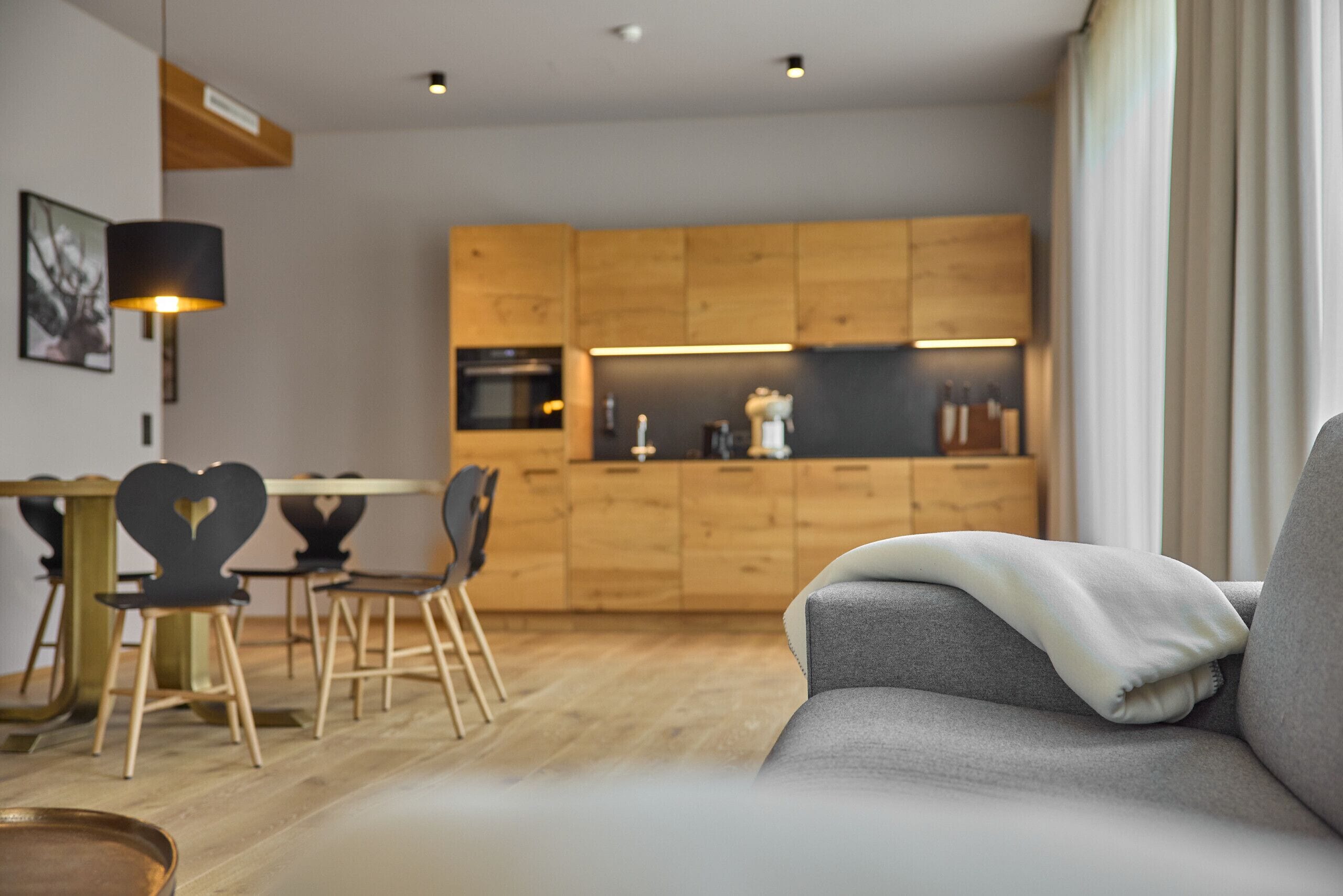 Una sala moderna con un sofá gris, una mesa de comedor de madera y sillas.