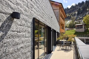 Ein modernes Gebäude mit einer Stein-Fassade, großen Glasfenstern und einem holzverkleideten Satteldach.