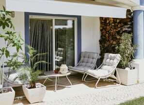 A patio with two lounge chairs, a small table, and potted plants. - Holiday appartment, work and stay, pool and gym equipment. (Sagres)