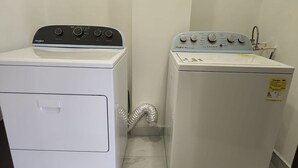 A laundry room with two Whirlpool washers, one with a control panel and the other with a water inlet.