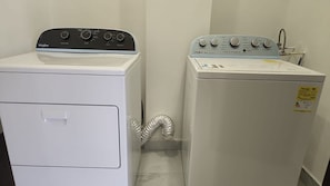 A laundry room with two Whirlpool washers, one with a control panel and the other with a water inlet.