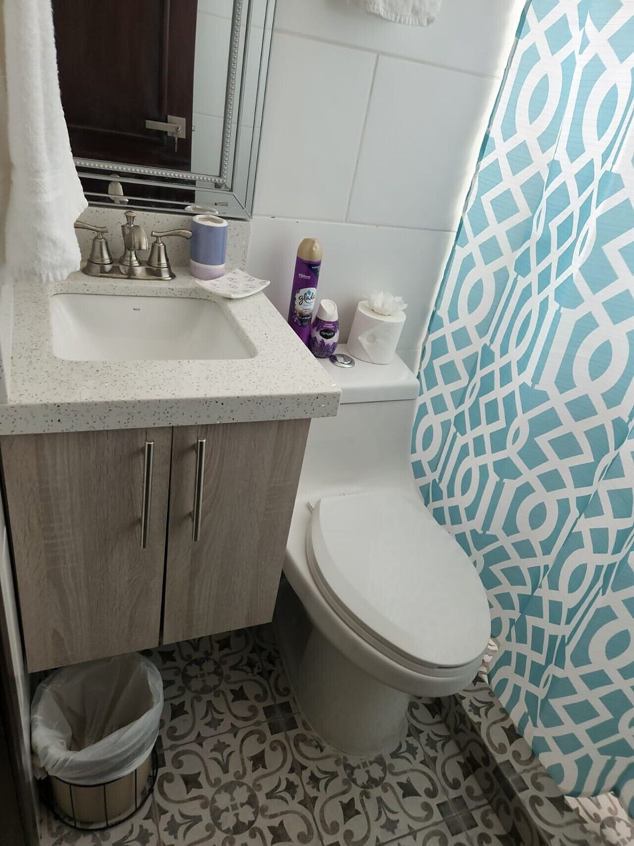 Une salle de bain avec un lavabo blanc, des toilettes et un rideau de douche à motifs.