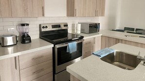 A modern kitchen with stainless steel appliances, wooden cabinets, and a white countertop.