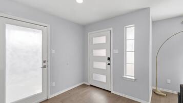 Una habitación con una puerta grande de color blanco, una puerta más pequeña con ventana y una lámpara de pie.