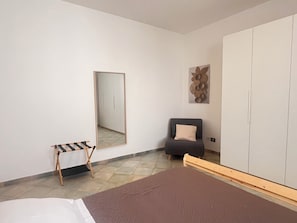A bedroom with a bed, a chair, a wardrobe, a mirror, and a small bench. - Casa Nicolas 158 - Salento Explorer (Neviano)