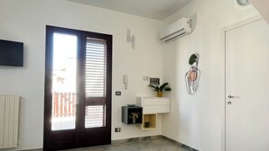 Ein Zimmer mit Tür, Wandklimaanlage, kleiner Pflanze und Fliesenboden.