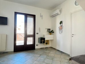 A room with a door, a wall-mounted air conditioner, a small plant, and a tiled floor. - Casa Nicolas 158 - Salento Explorer (Neviano)