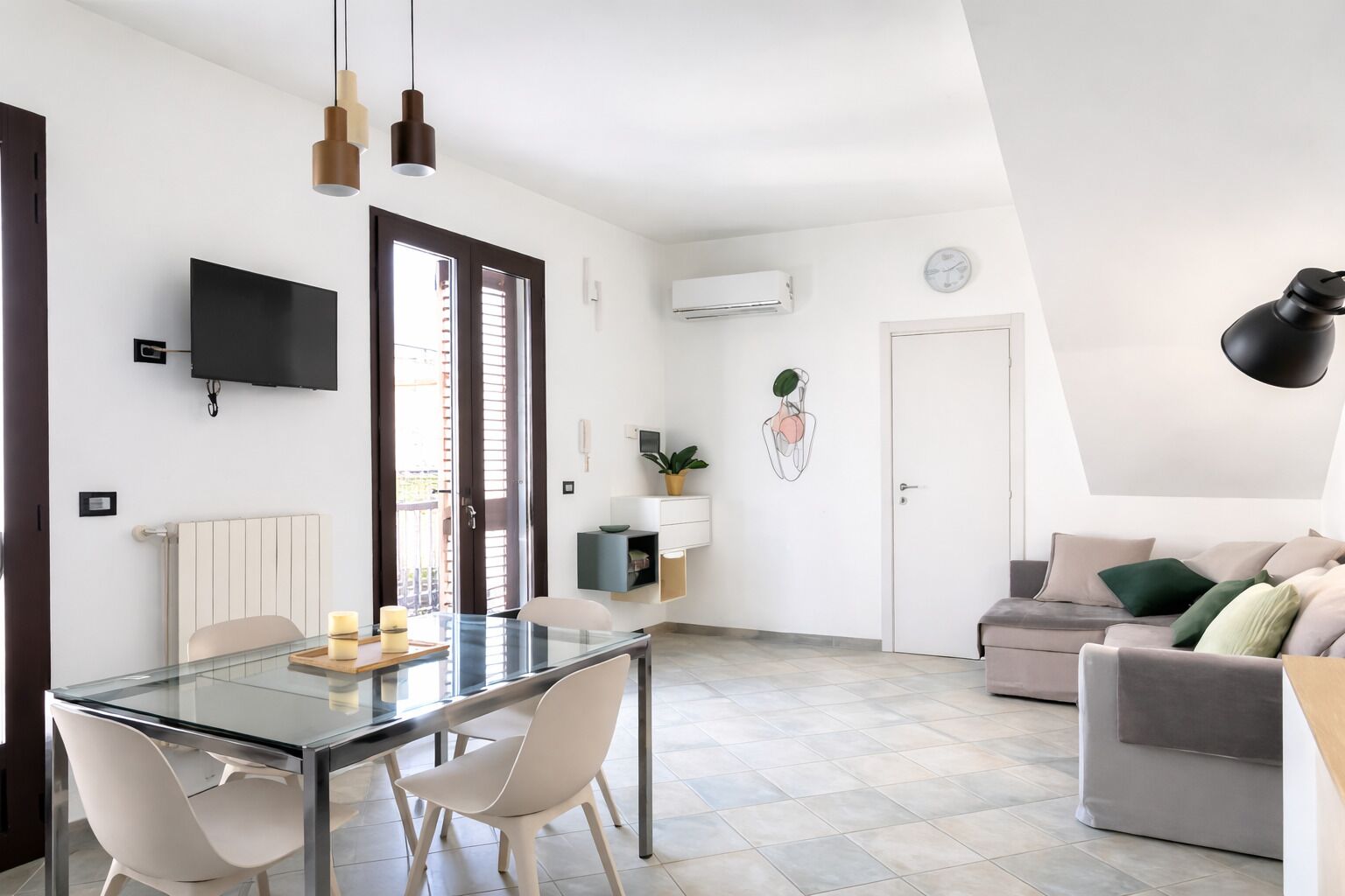 Ein moderner Wohnraum mit einem Glastisch, einer Couch und einem an der Wand befestigten Fernseher.
