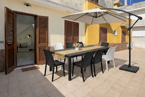 An outdoor dining area with a table, chairs, and an umbrella. - Casa Nicolas 158 - Salento Explorer (Neviano)
