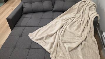 A grey sofa with a beige throw blanket.