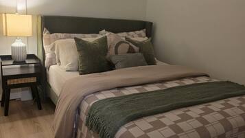 A bedroom with a bed, a nightstand, a lamp, and a window with blinds.