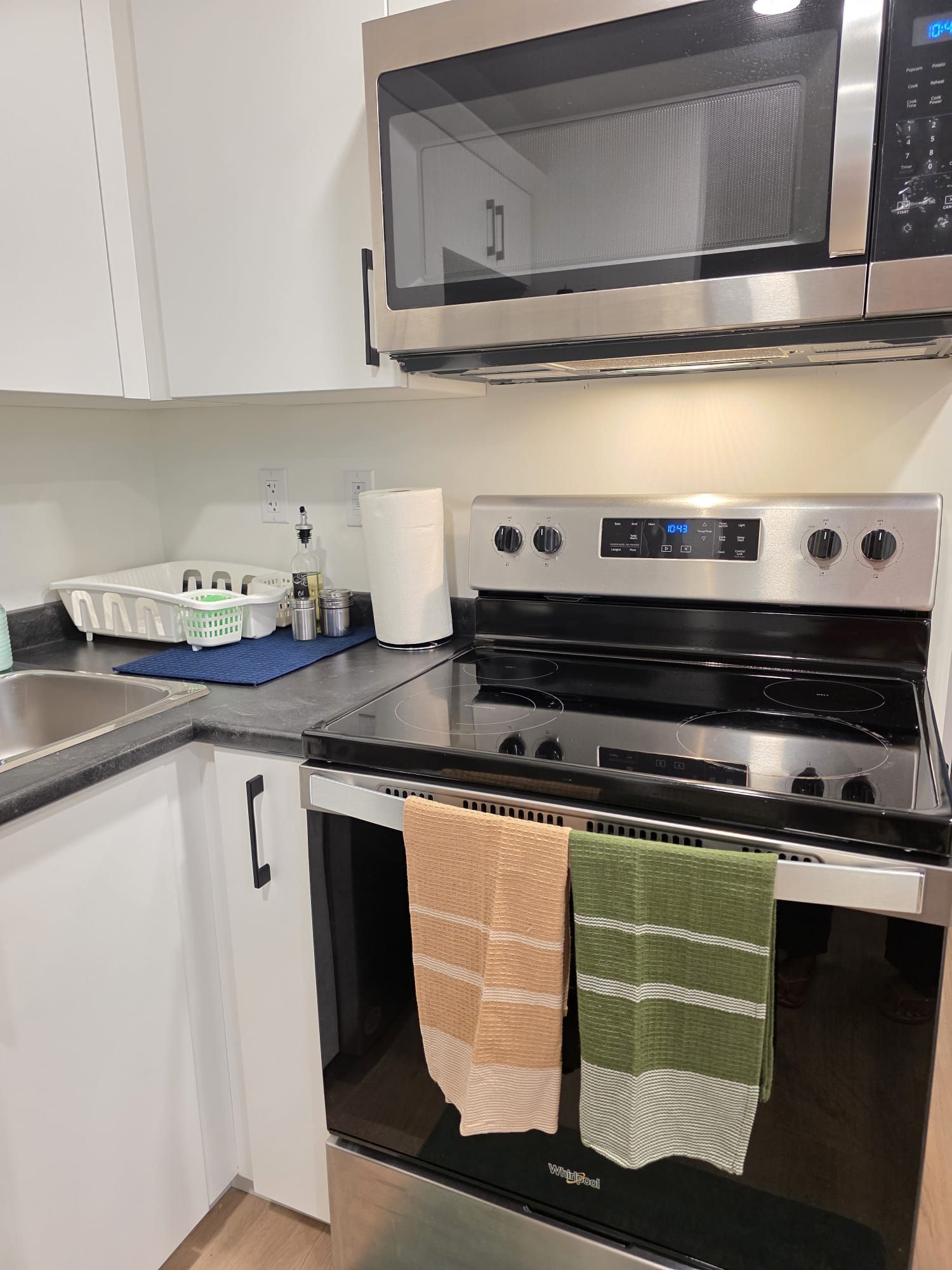 A kitchen with a microwave, oven, and a sink.