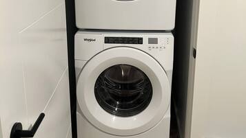 Een gestapelde wasmachine en droger met een zichtbare bedieningspaneel en een deurklink.