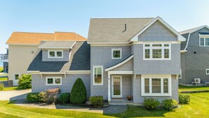 A two-story residential house with a grey siding exterior, a sloped roof, and a front porch. - New Beautiful Estate, Steps to Ocean, Sleeps 12 (Saco)