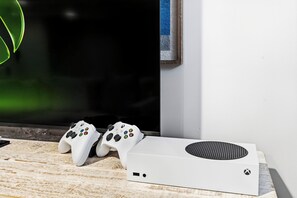 A white Xbox console and controllers on a wooden surface next to a television. - New Beautiful Estate, Steps to Ocean, Sleeps 12 (Saco)