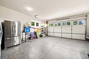 Eine Garage mit einem großen, edelstahlfarbenen Kühlschrank, einem Fenster und einer Garagentür.