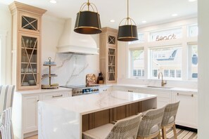 Een ruime keuken met een groot eiland, houten kastjes en uitzicht op buiten.
