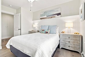 Ein Schlafzimmer mit einem großen Bett, zwei Nachttischen, einem Beistelltisch, einem Deckenventilator und einer Wandleuchte.