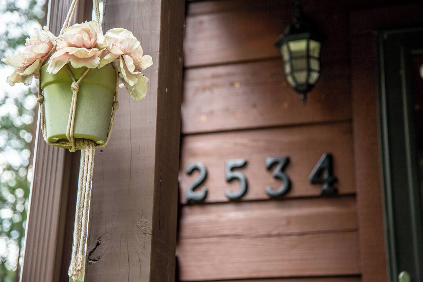 Fachada de madera con una maceta colgante y un farol.
