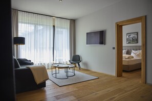 Ett modernt vardagsrum med en soffa, en fåtölj, ett soffbord och en säng med en tavla på väggen.