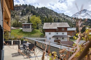 Ein Wohngebiet mit Bergblick, ein Holzhaus und eine gepflasterte Terrasse mit Gartenmöbeln.