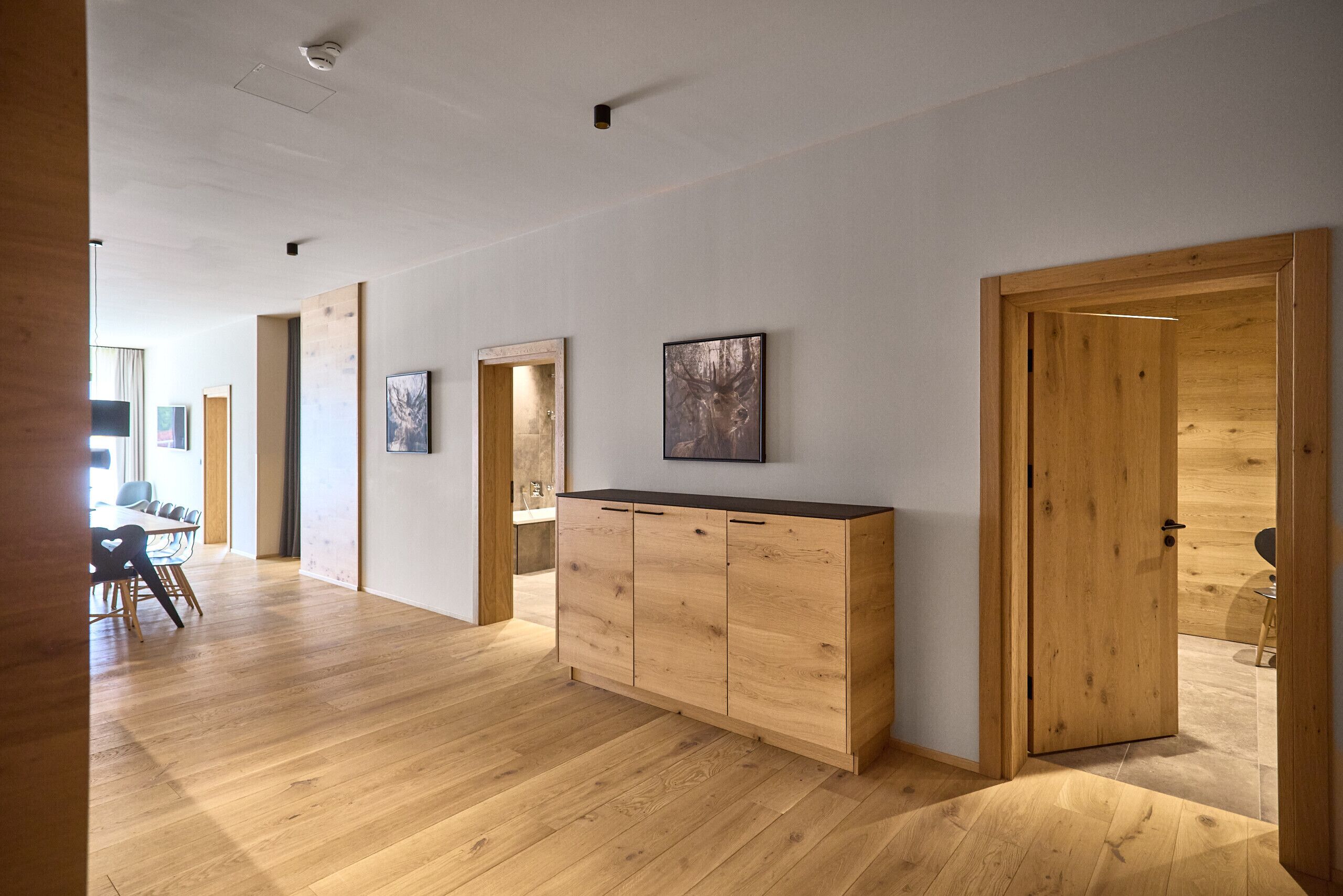 Una habitación amplia con suelo de madera, un mueble grande de madera y una puerta que da a otra zona.