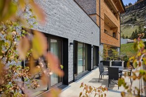 Un bâtiment moderne doté de grandes fenêtres en verre et d’un patio aménagé avec du mobilier d’extérieur.