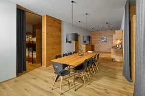 Ein moderner Essbereich mit Holztisch und -stühlen, einer Pendelleuchte und Blick ins Schlafzimmer.