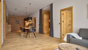 En modern inredning med en matplats i trä, en grå soffa och en fjärrkontroll på ett litet bord.