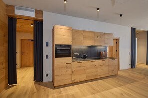 A modern kitchen with wooden cabinetry, a built-in oven, and a coffee machine. - 8003 Arlberg Private Retreat 3 (Schröcken)