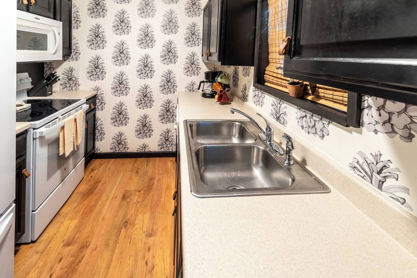 A compact kitchen with a double sink, a microwave, and a stove.