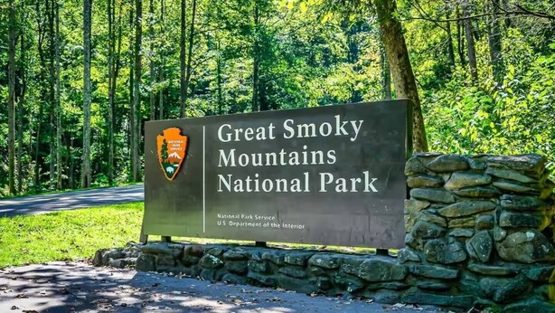 A sign for Great Smoky Mountains National Park with a logo and text indicating it's managed by the National Park Service and the U.S. Department of the Interior. - Family-Friendly Smoky Mountain Retreat | Hot Tub (Sevierville)
